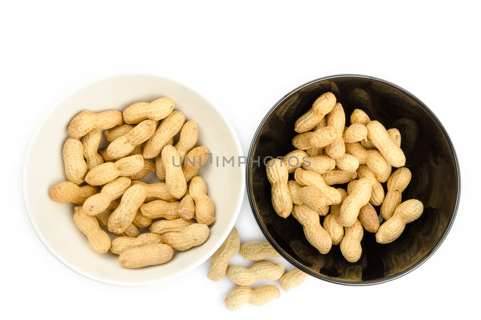 Black and white bowls full of peanuts on a white background by velislava