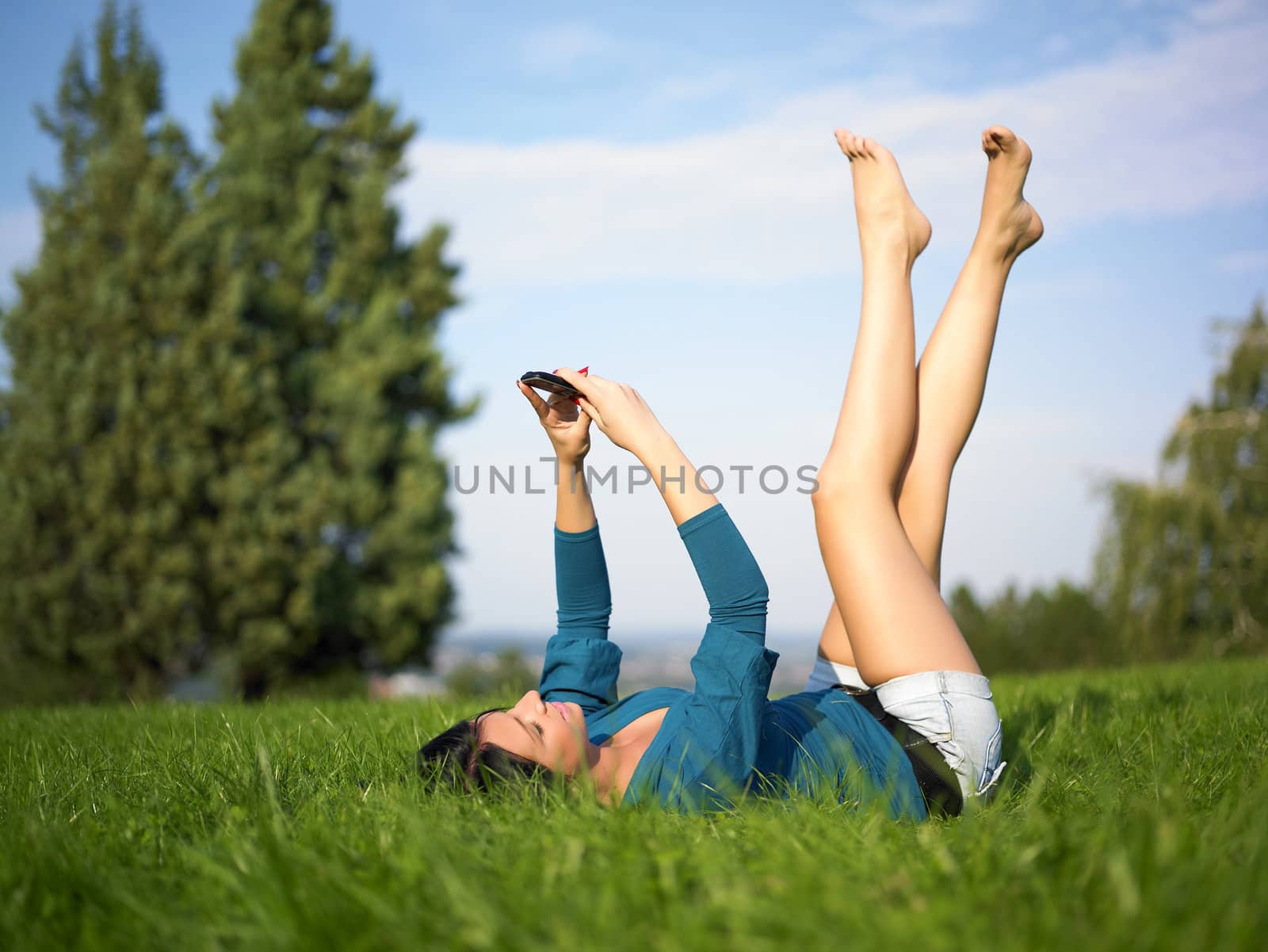 Young woman using mobile phone in park by adamr