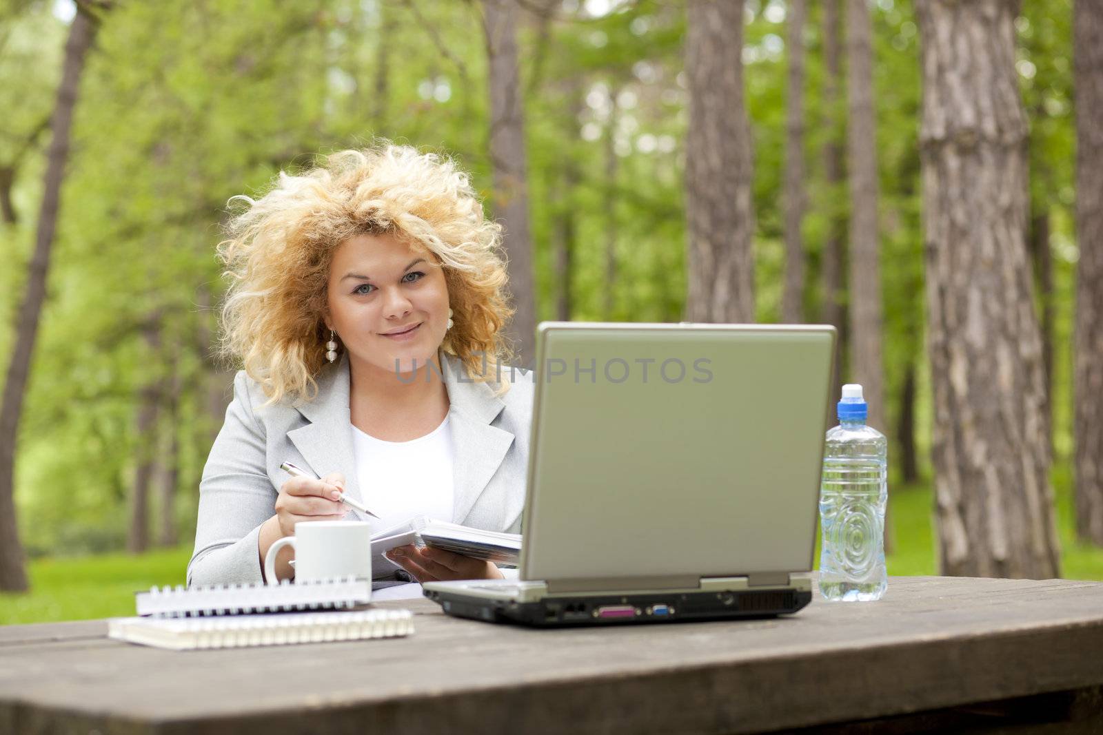 Woman using laptop in park on wooden table by adamr