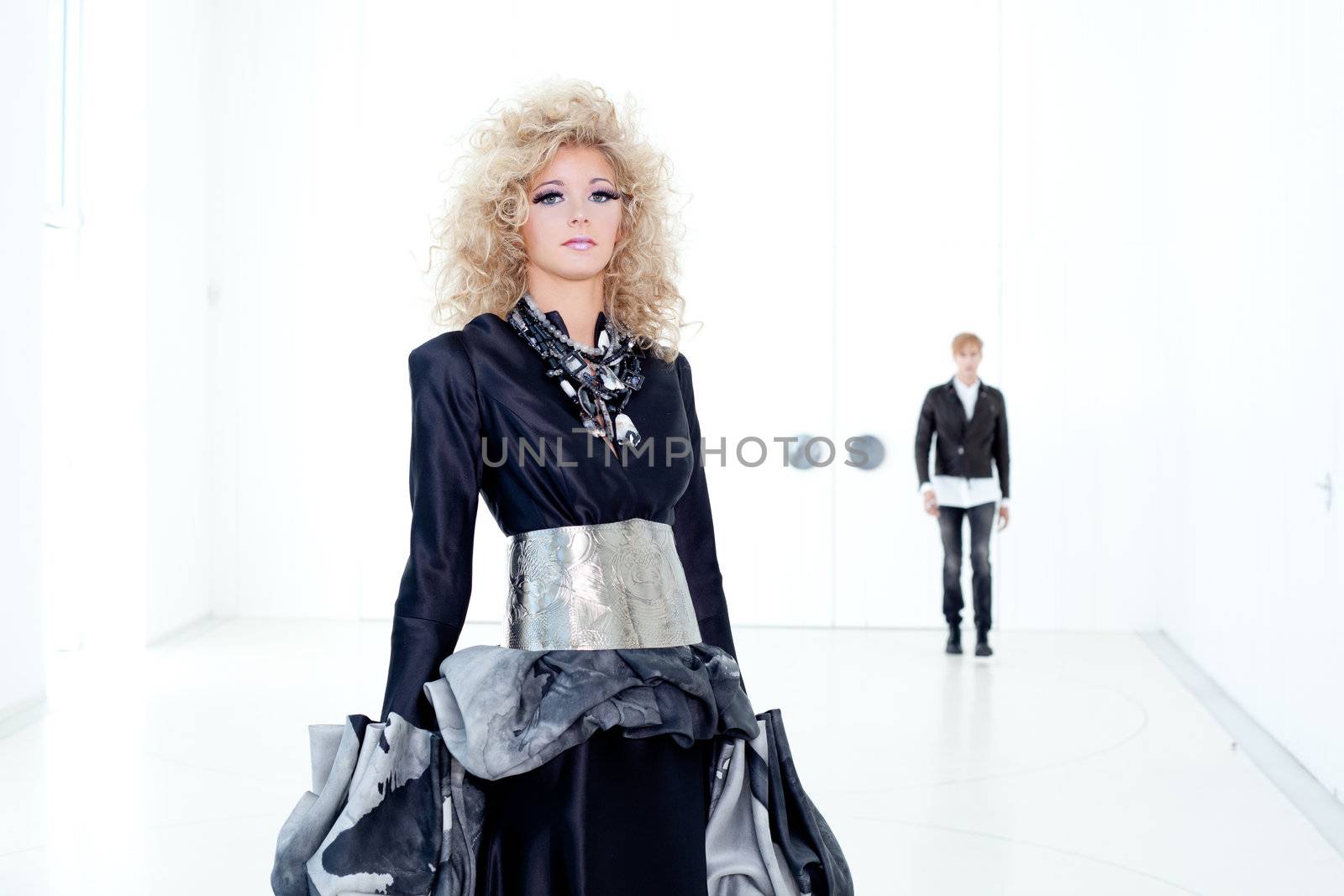 Black haute couture retro futurist couple in modern white hall with vampire inspiration