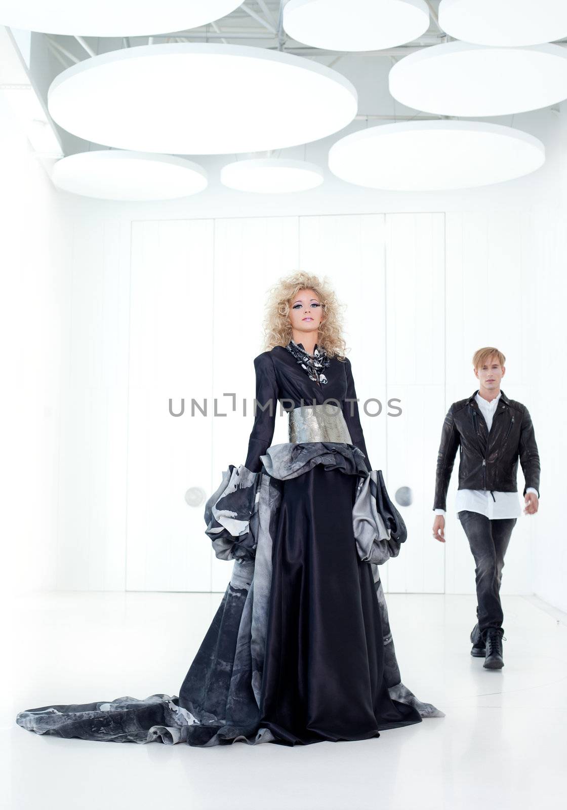 Black haute couture retro futurist couple in modern white hall with vampire inspiration