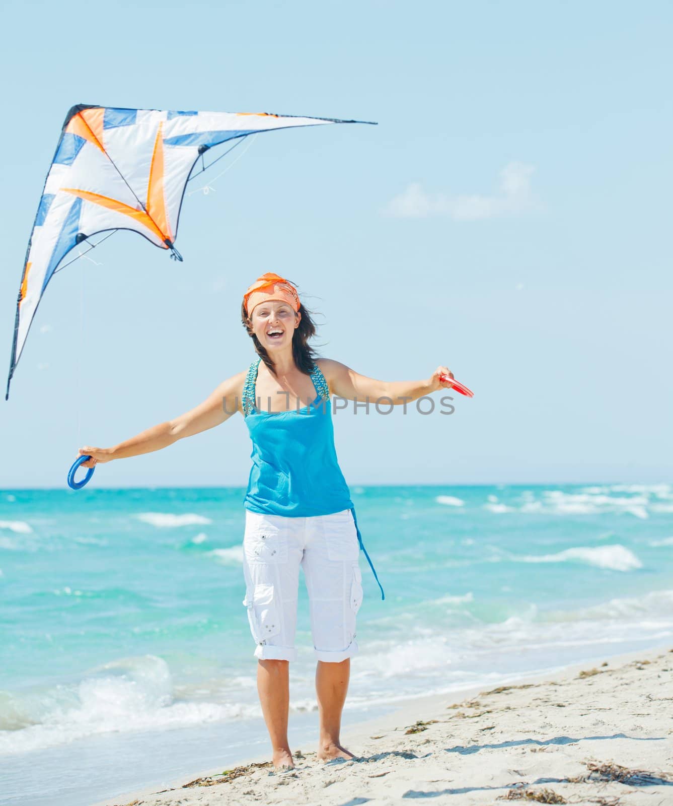 Young cute woman playing with a colorful kite on the tropical beach. Vertikal veiw