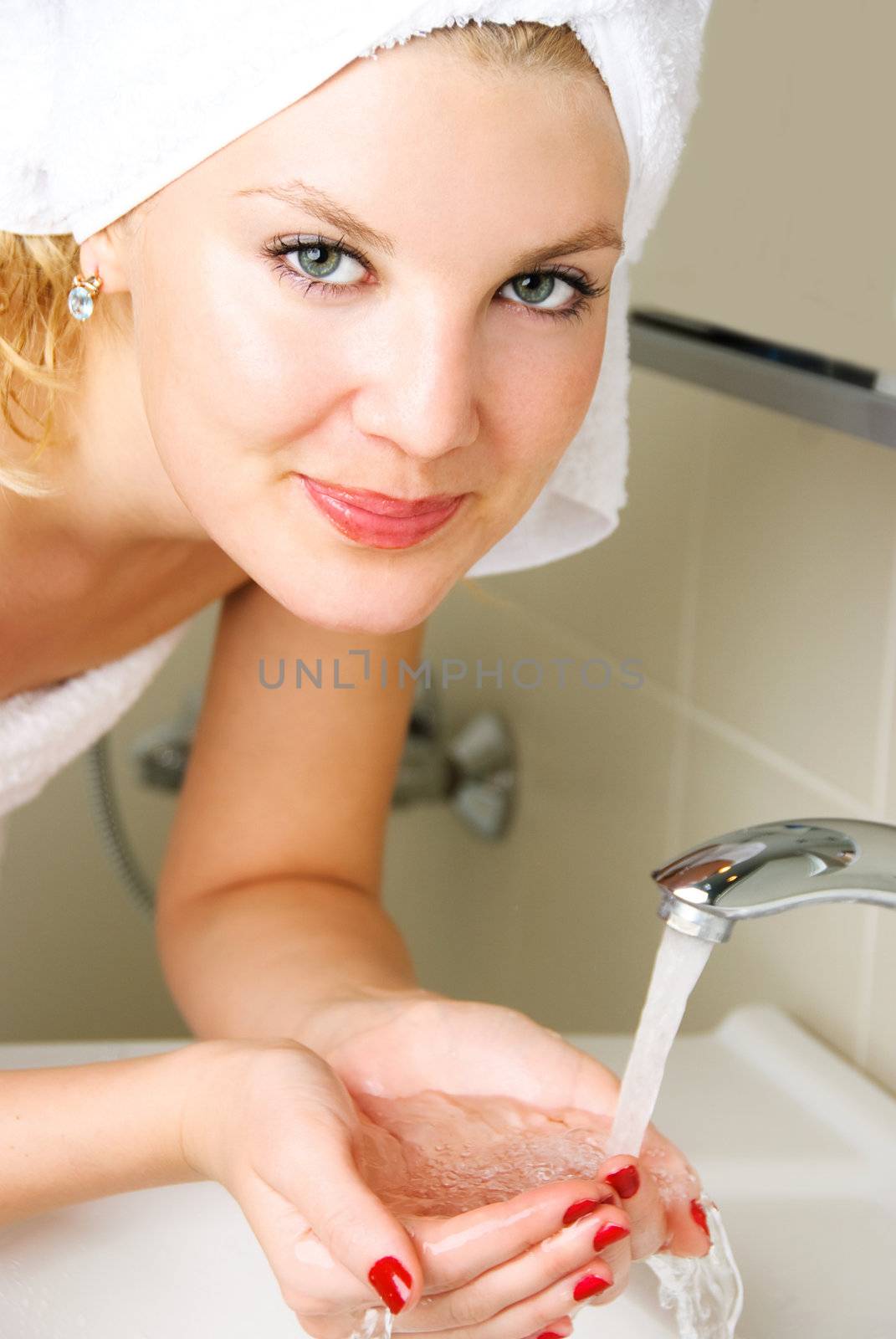 beautiful happy young woman washing her face in the bathroom