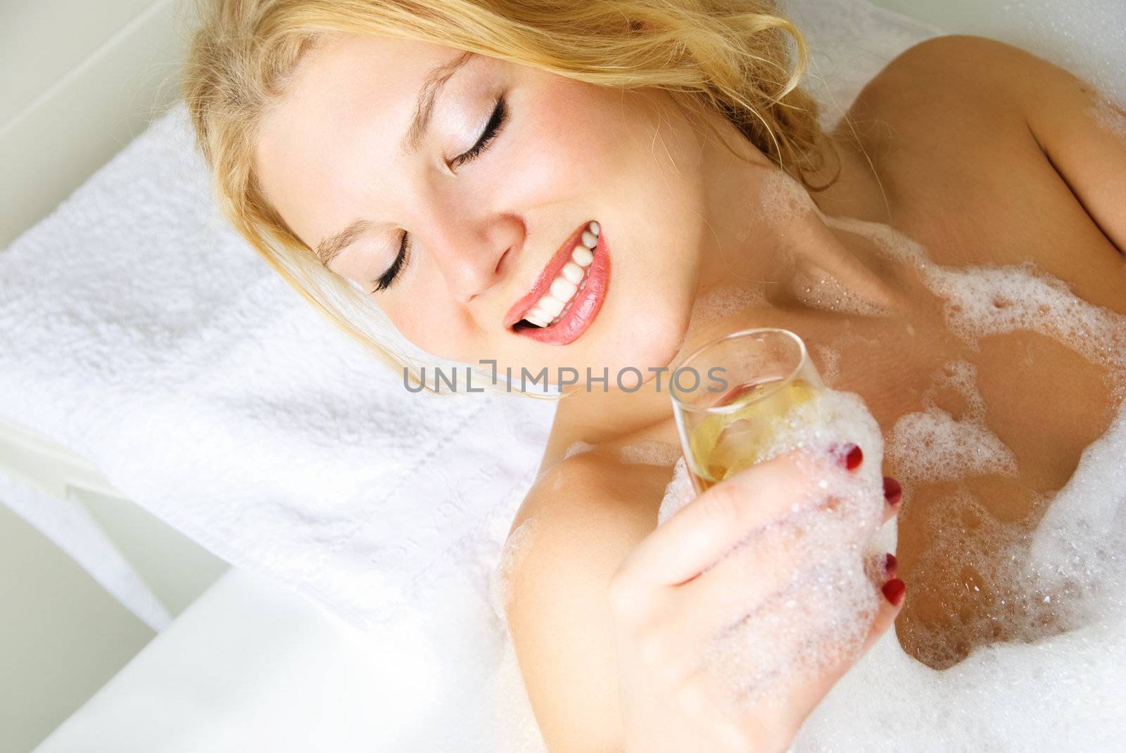 beautiful happy young woman taking a bath with a glass of champagne