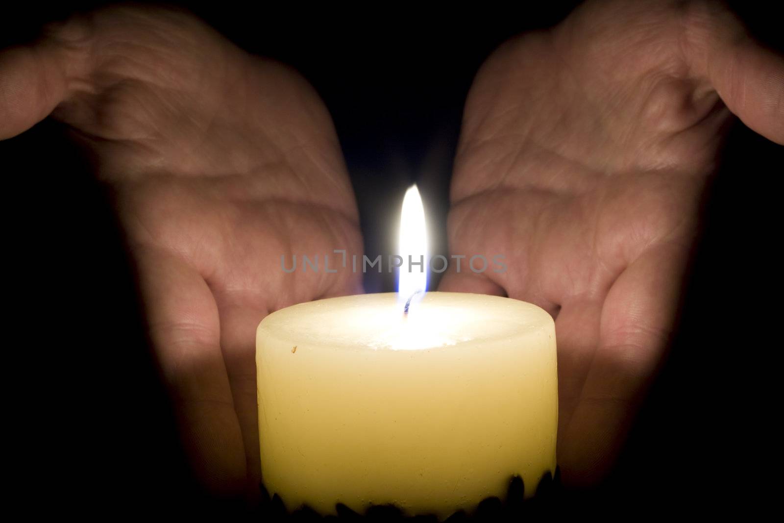 Human hands and candle in the night