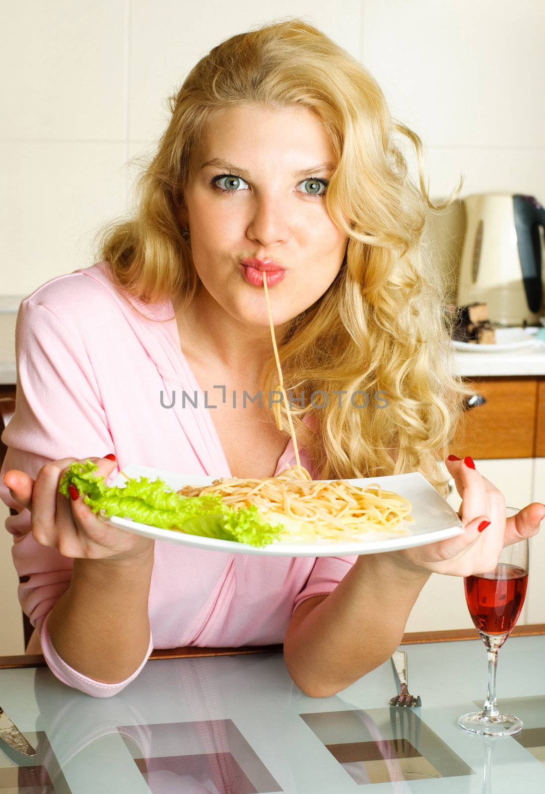 beautiful young woman at home in the kitchen eating spaghetti