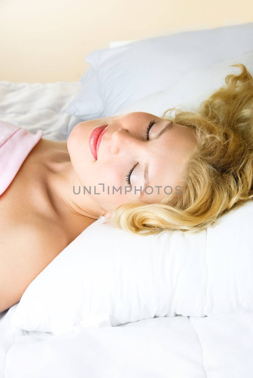 beautiful young blond woman sleeping in her bed at home