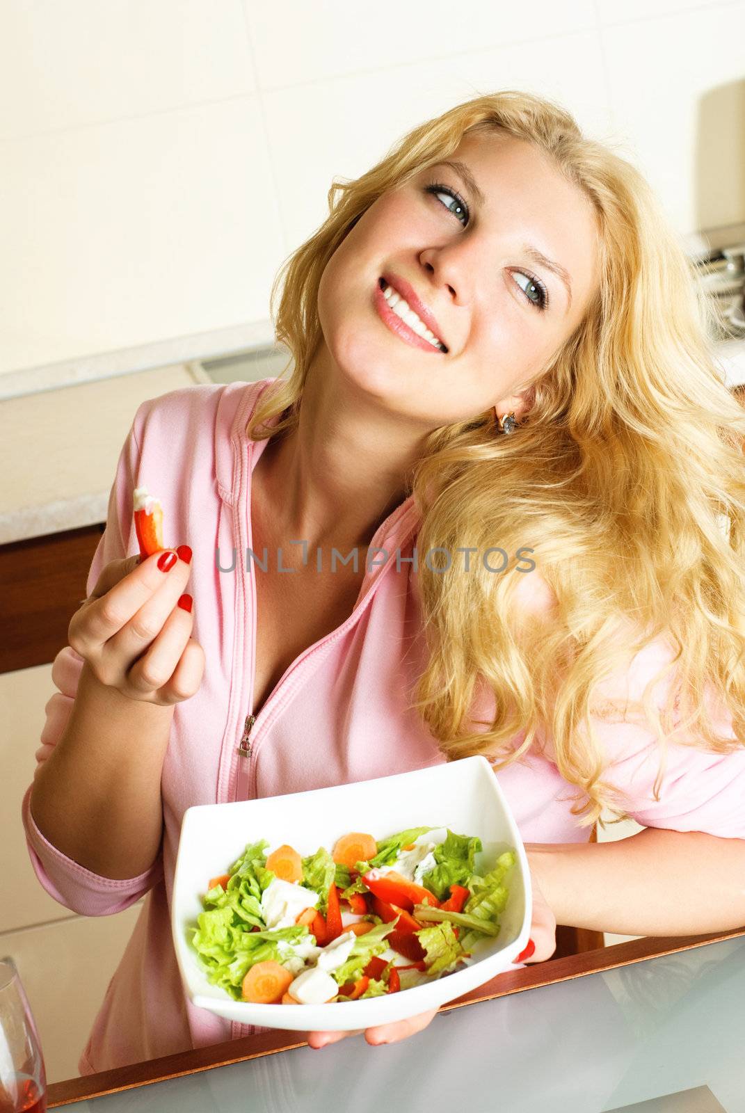 pretty young woman at home in the kitchen eating salad 