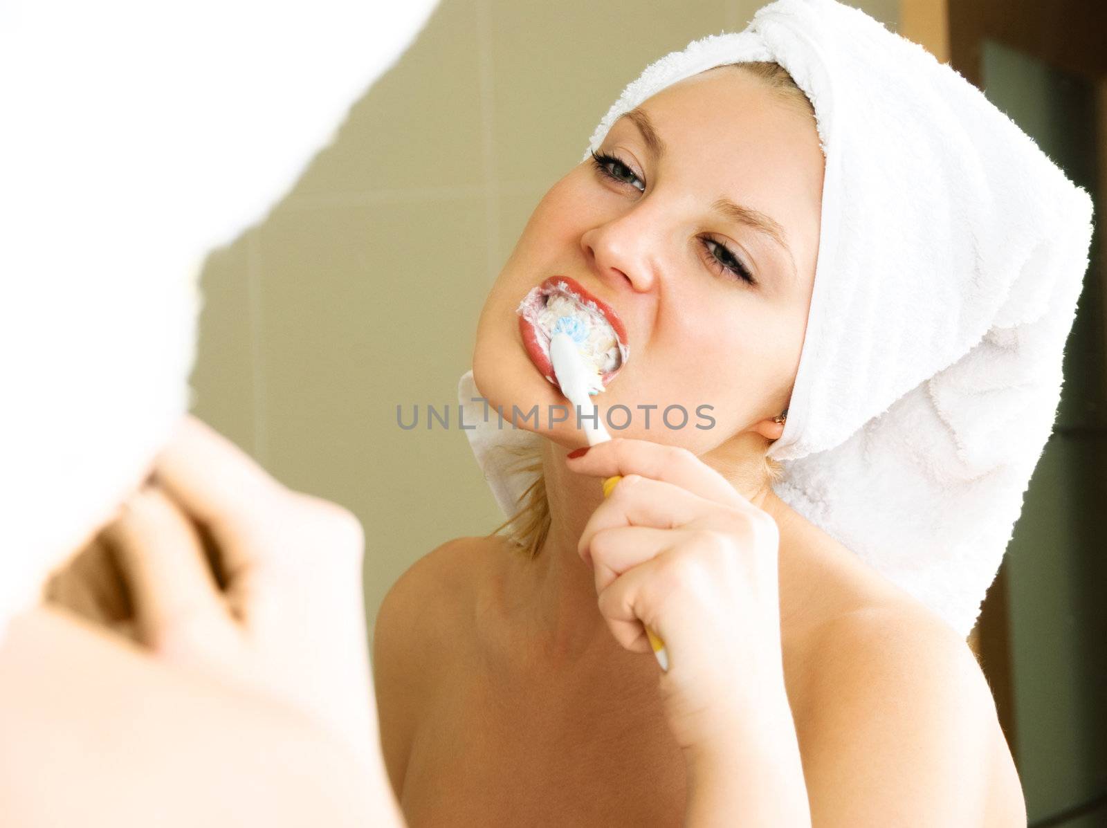 pretty girl at home looking into the mirror and brushing teeth