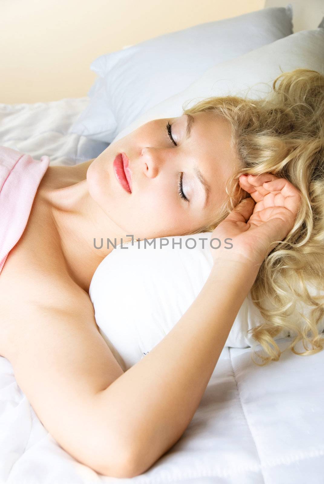 beautiful young blond woman sleeping peacefully in her bed at home