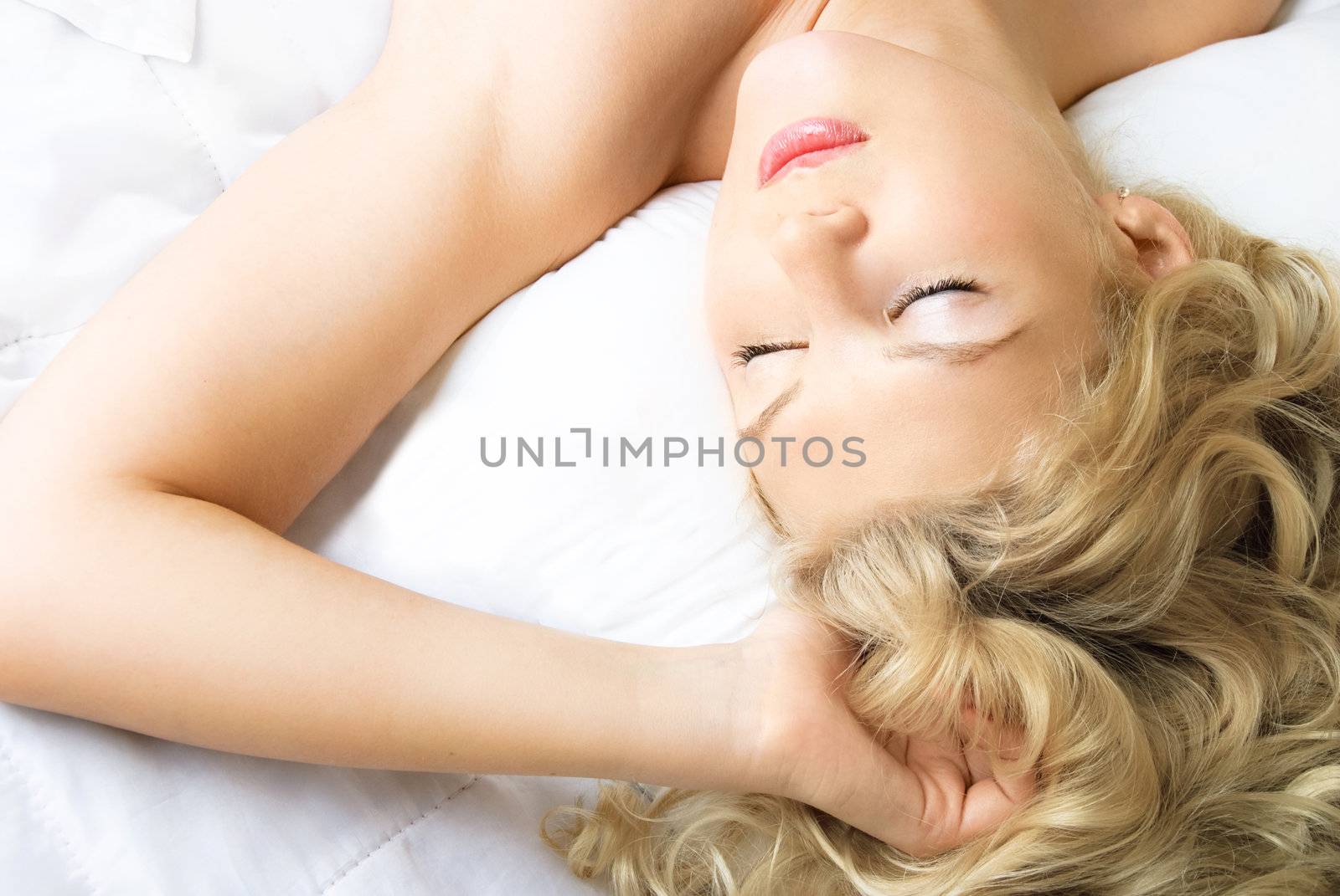beautiful young blond woman sleeping on the shite sheets