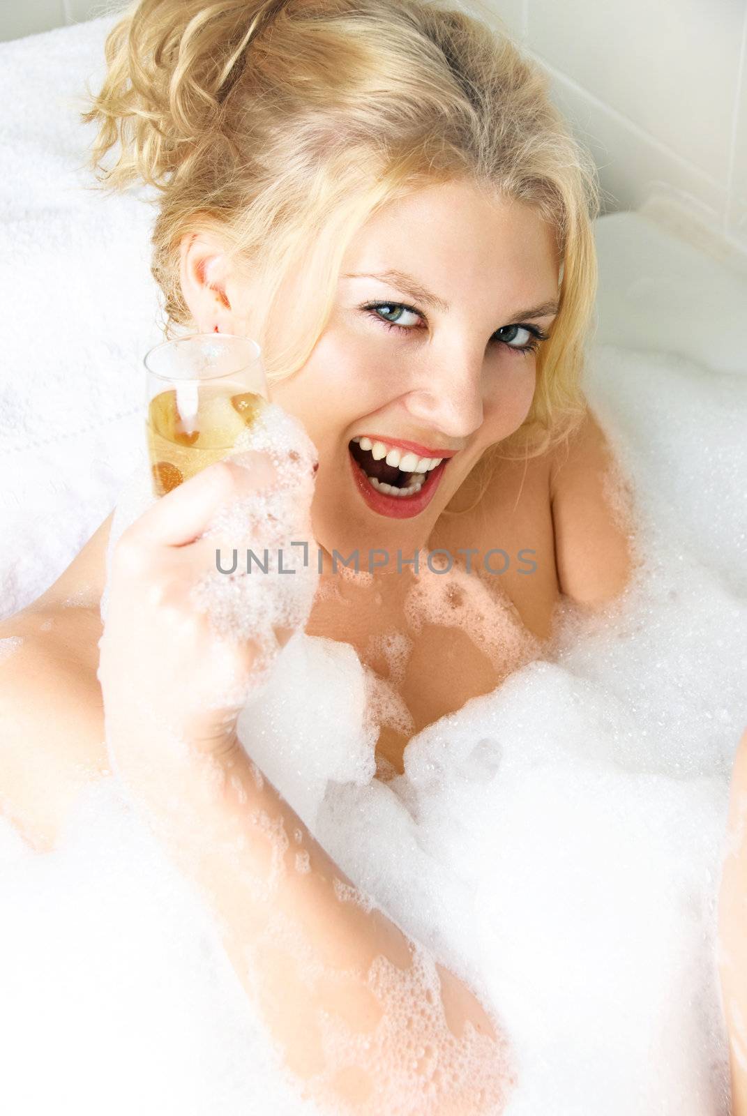 happy beautiful girl relaxing in a bath with a glass of champagne