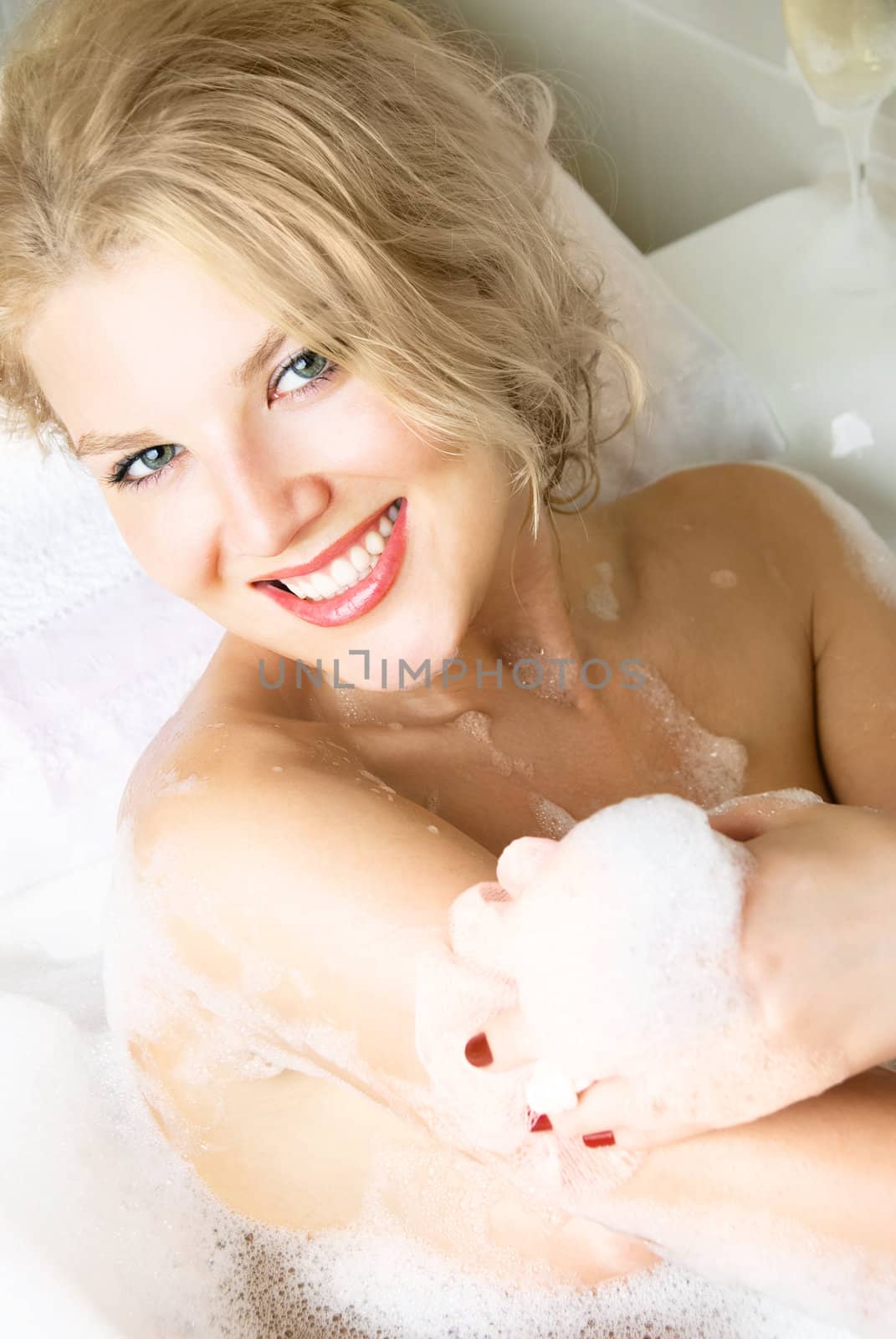 beautiful young blond woman relaxing in a bath with foam