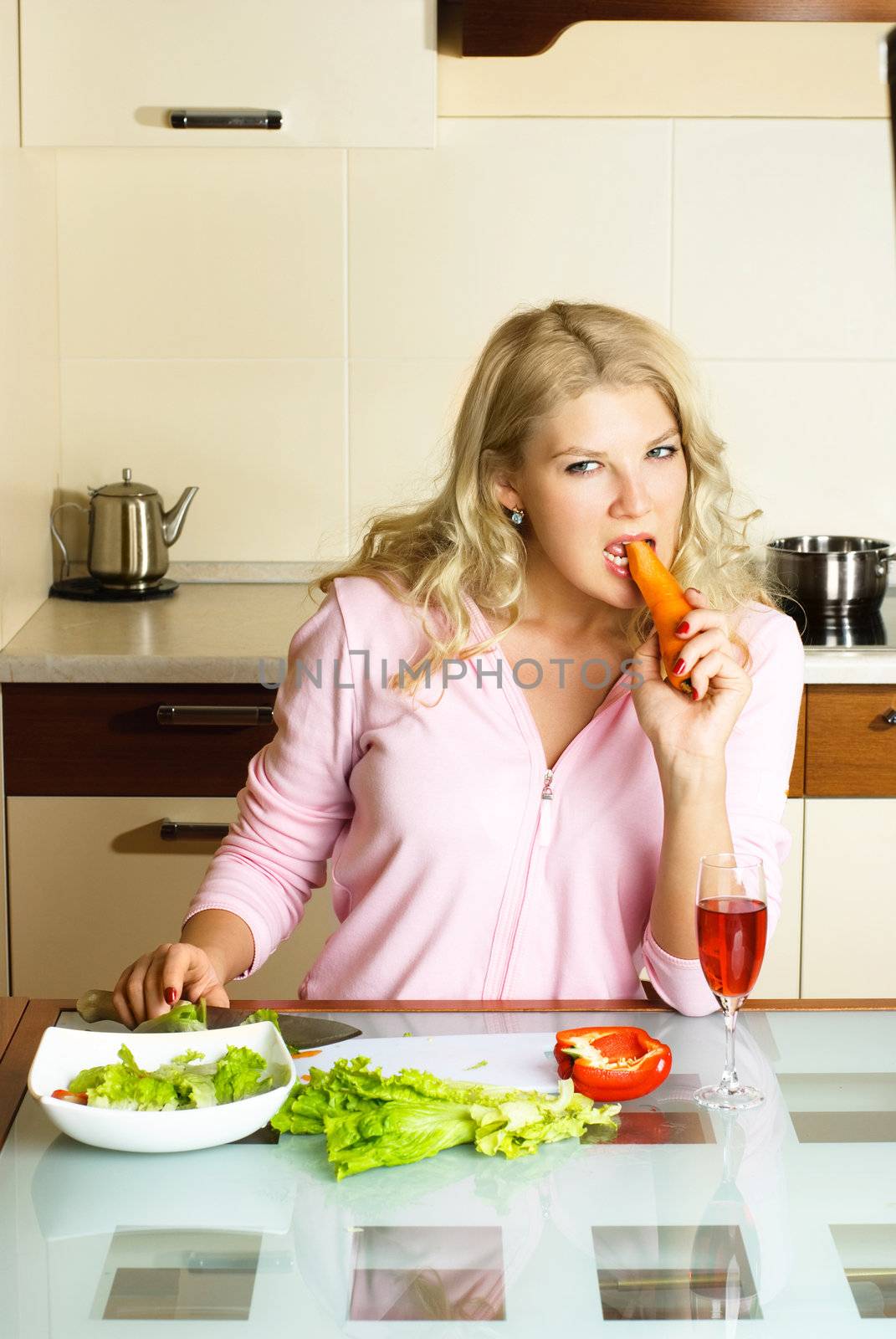 sad young woman at home in the kitchen keeping a diet and eating vegetables