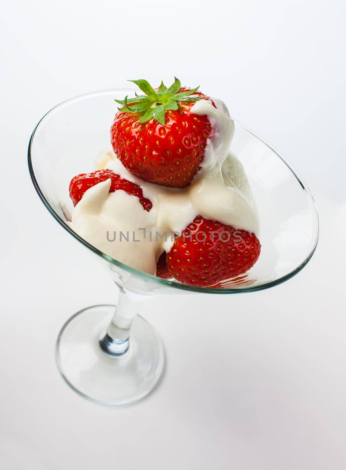 Strawberries with whipped cream and mint leaf in a glass on a white background