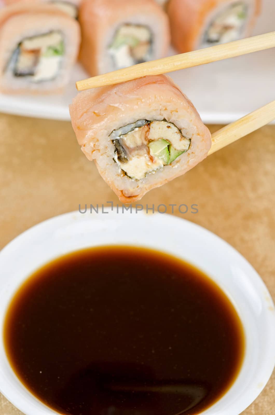 hand holding sushi with chopsticks at table