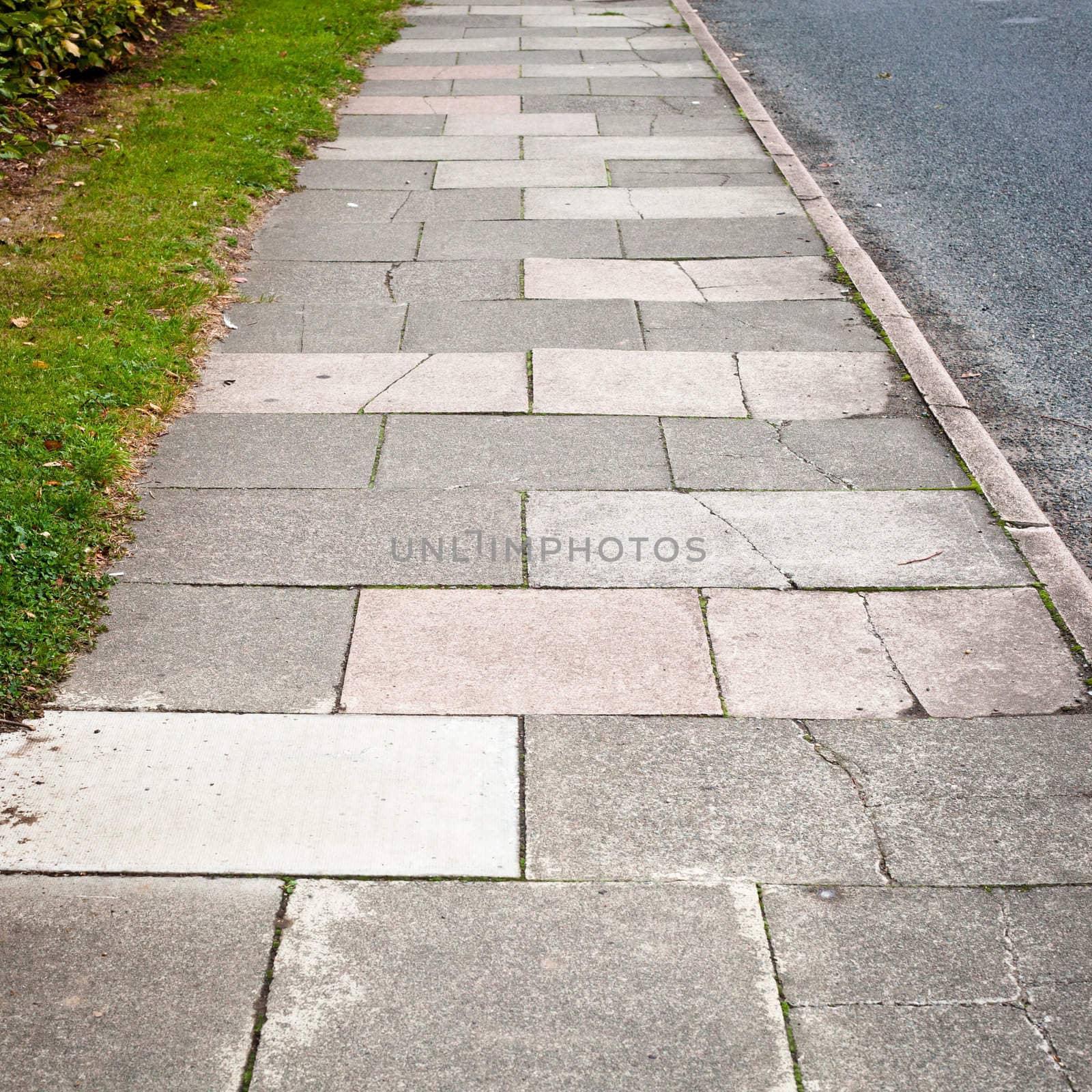 Details of a sidewalk between a road and a green grass verge