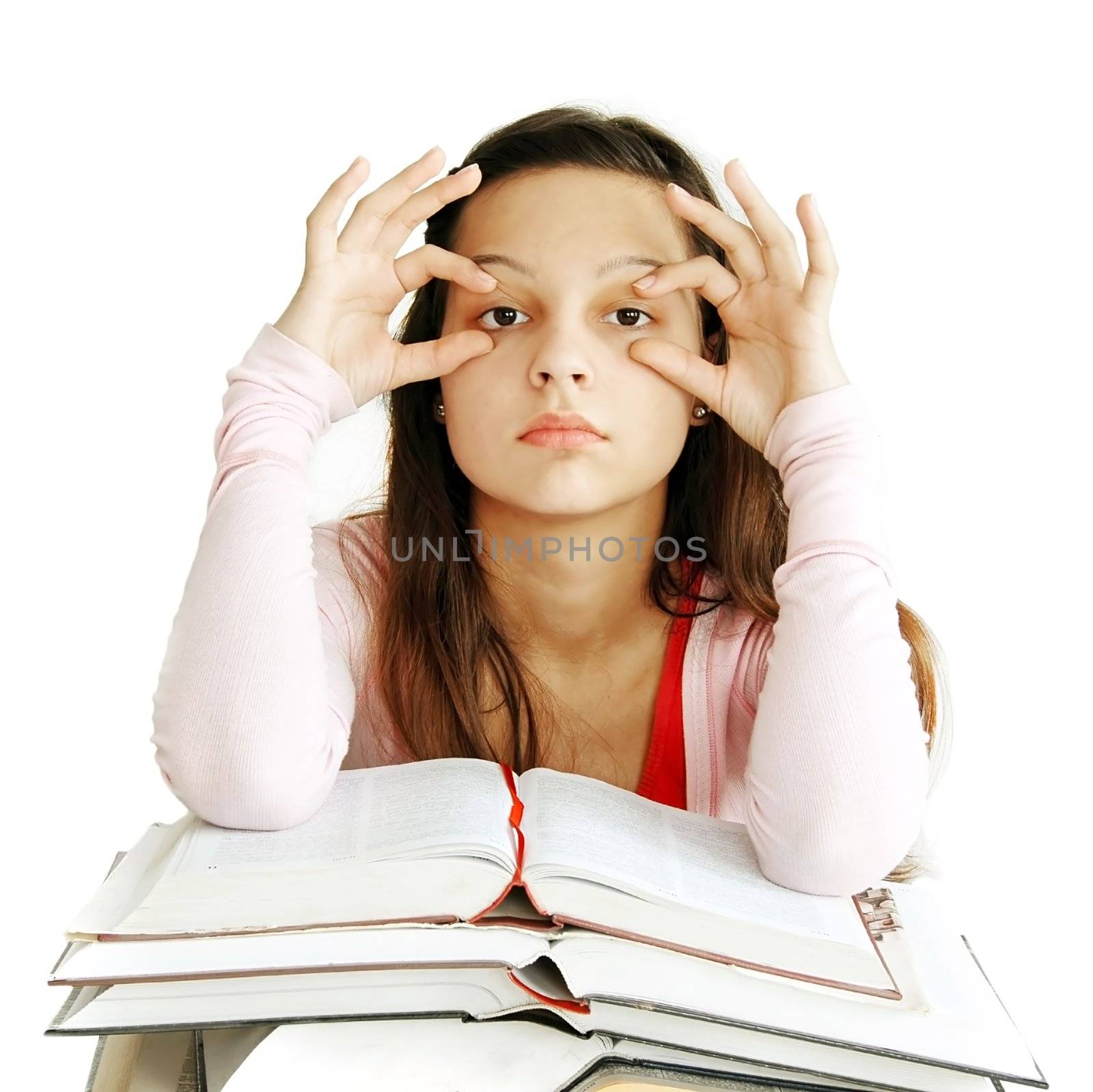 tired caucasian teenage girl sitting at the desk with arms holding eyes opened