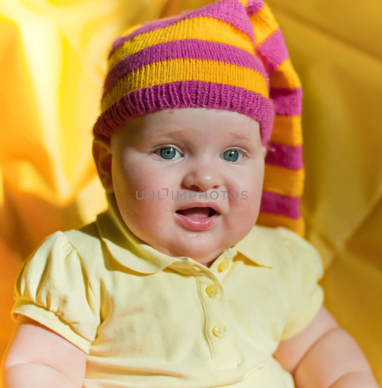 Surprised baby in the yellow and pink hat