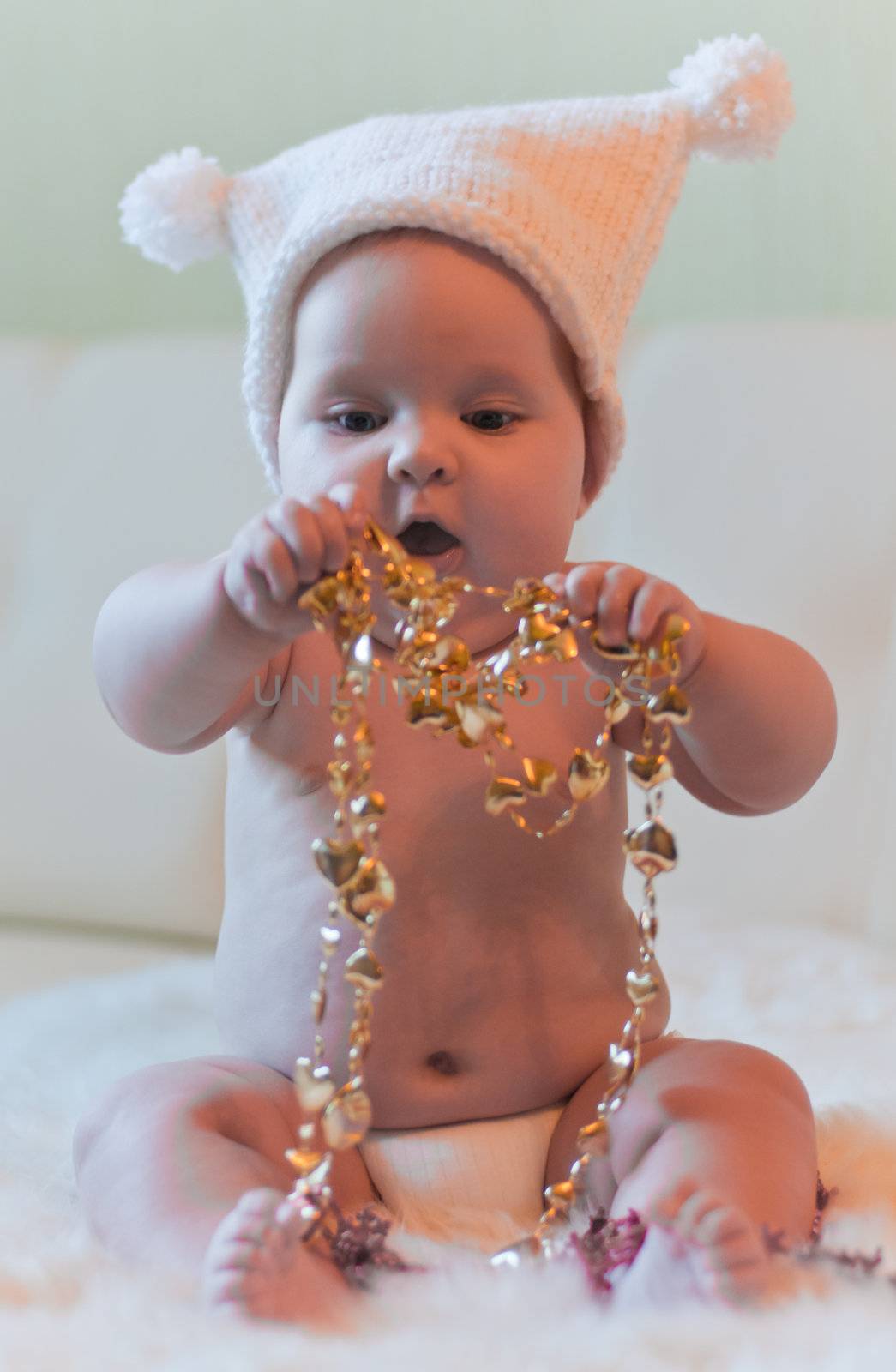 Baby in hat plays with gold tinsels