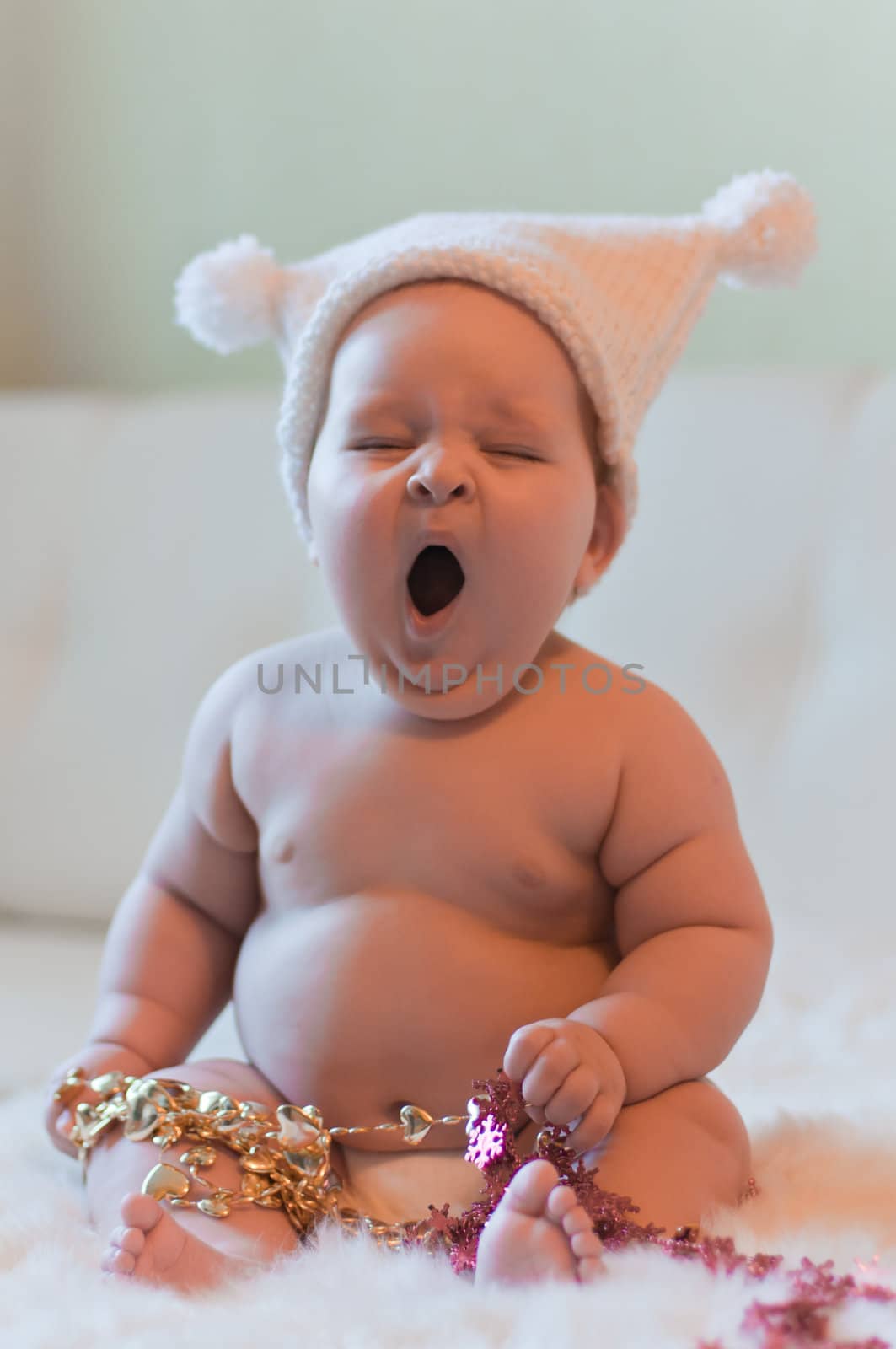 Portrait of yawning baby in hat with tinsel