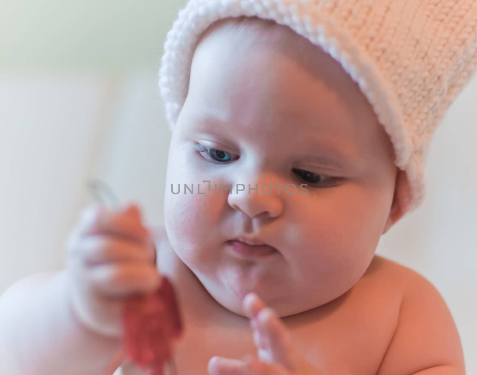 Baby in hat plays with red tinsels