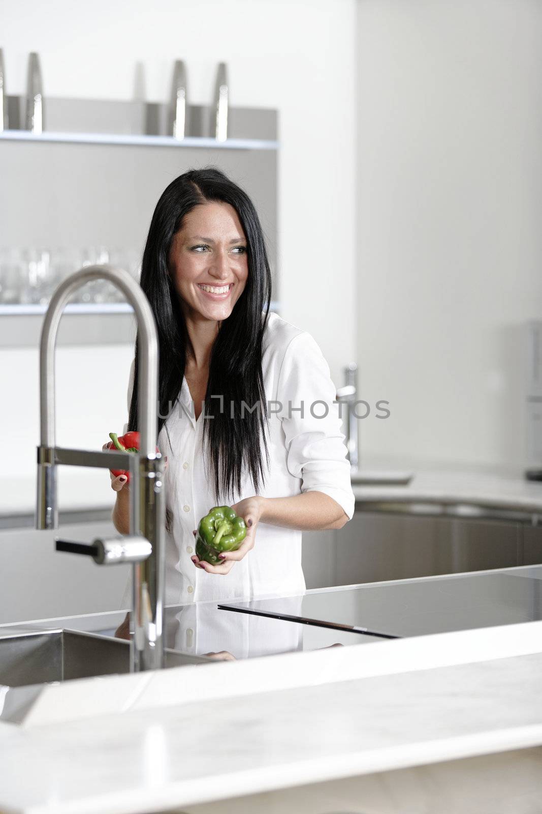Beautiful young woman preparing food in her modern kitchen at home