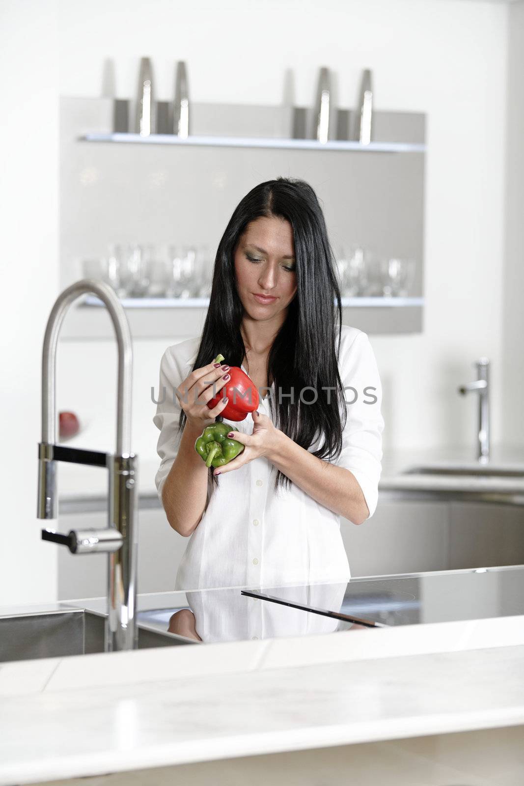 Woman rinsing peppers in a sink by studiofi