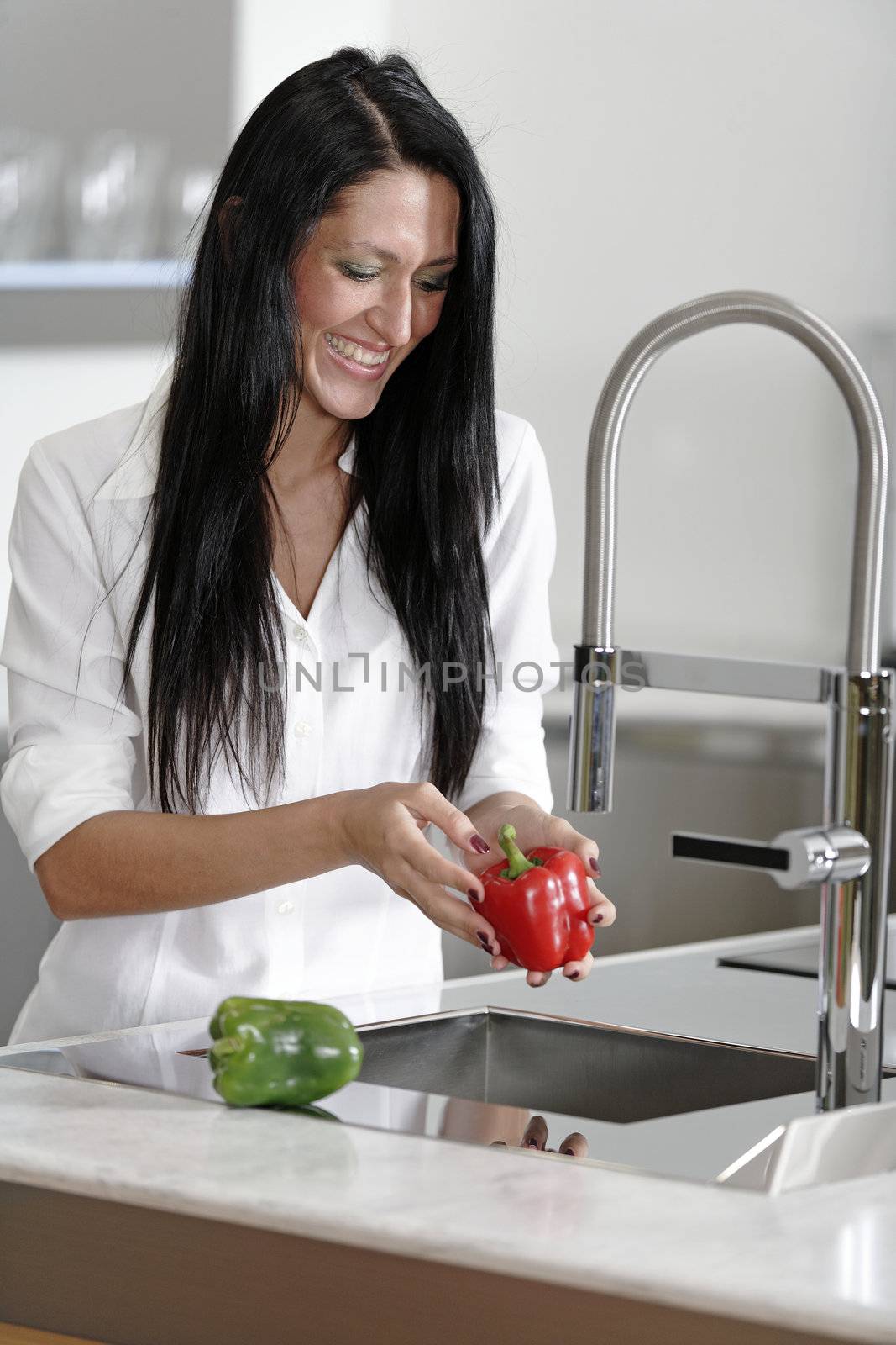 Woman rinsing peppers in a sink by studiofi