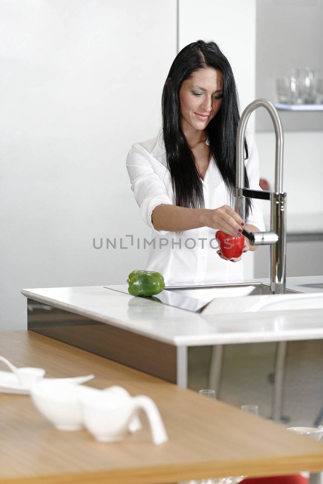 Beautiful young woman preparing food in her modern kitchen at home