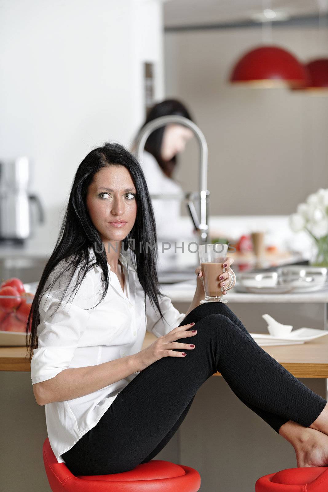 Two friends catching up over coffee in their kitchen.