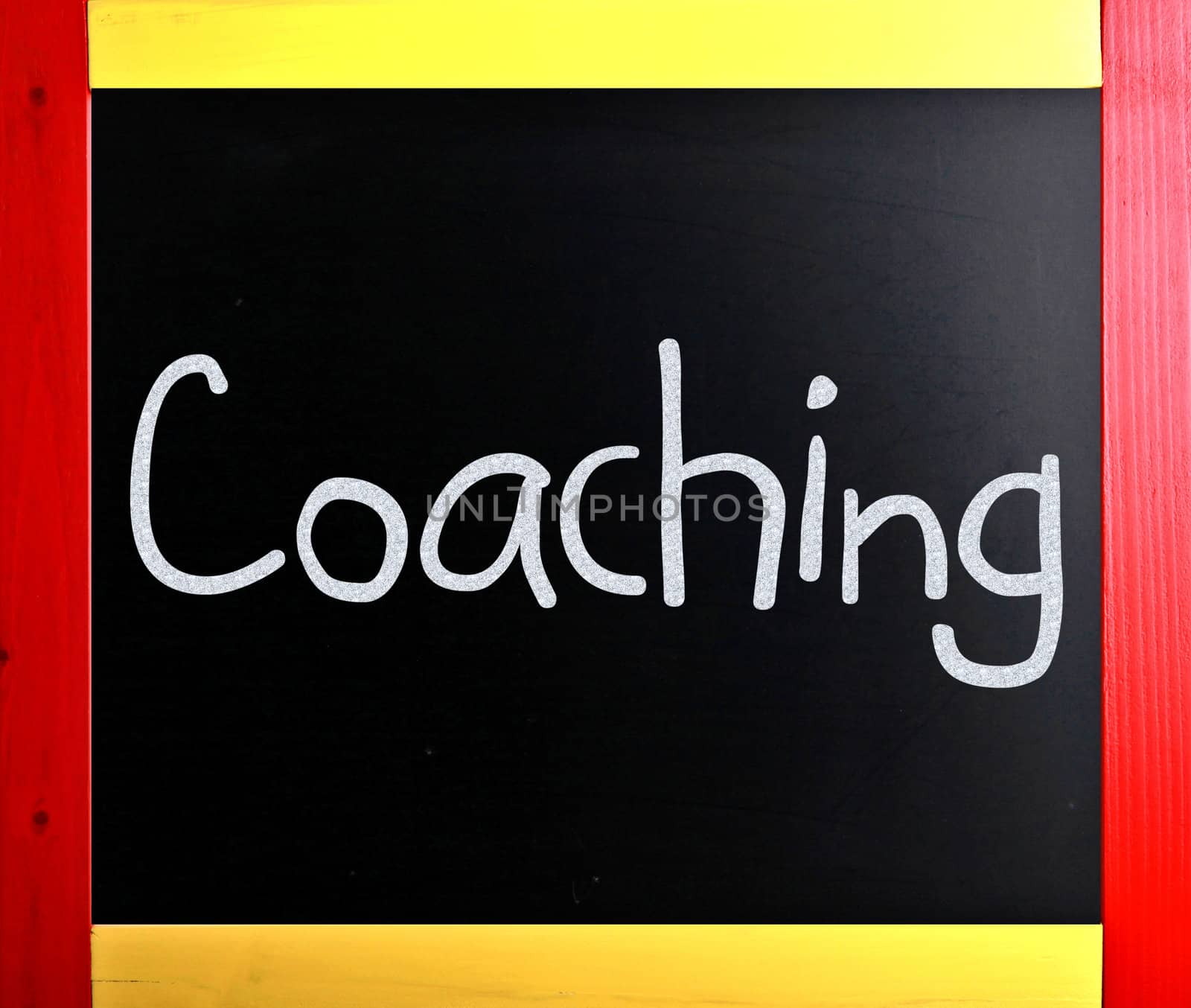 "Coaching" handwritten with white chalk on a blackboard