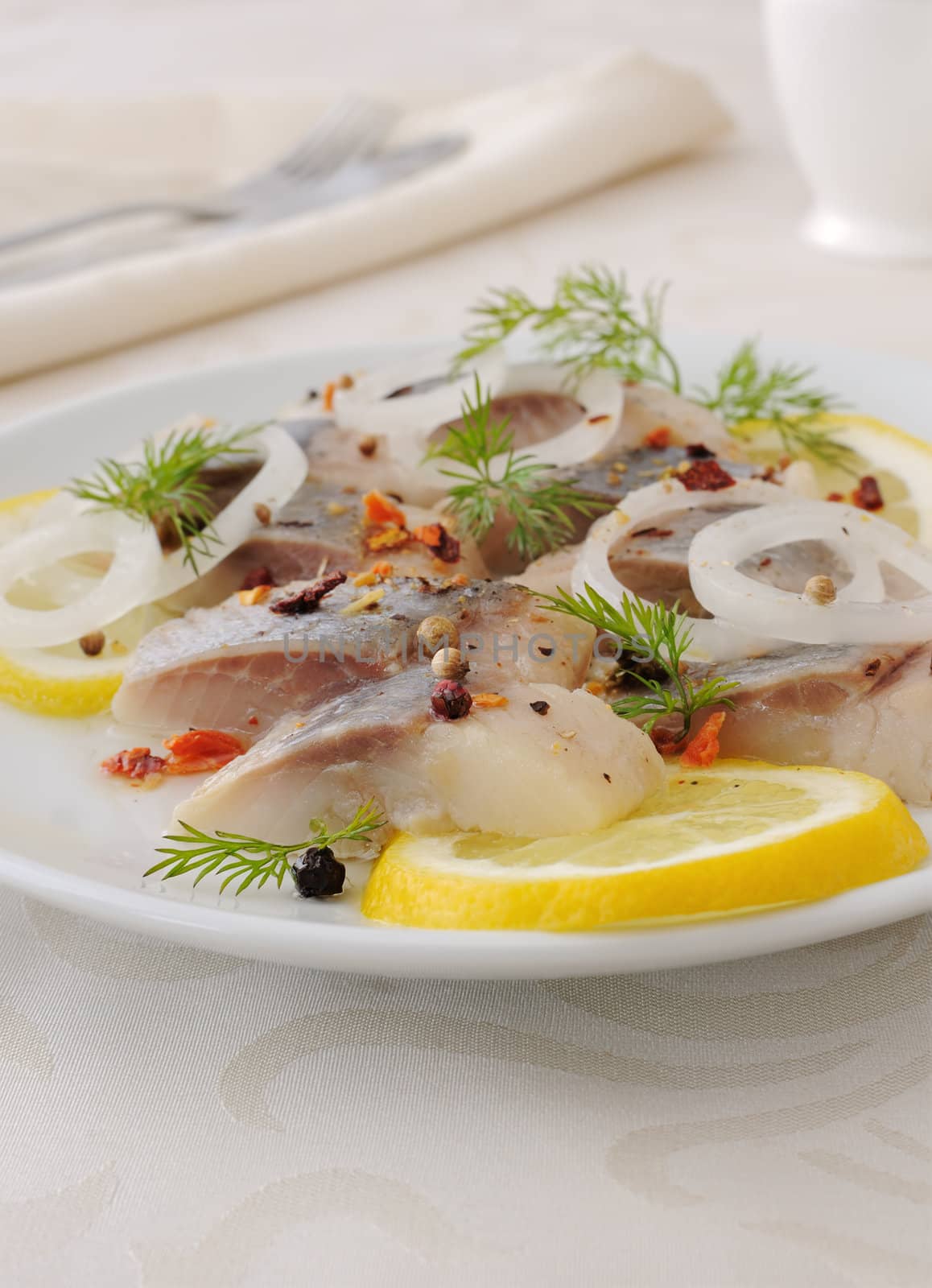 Slices of salted herring fillet with onion, lemon and spices

