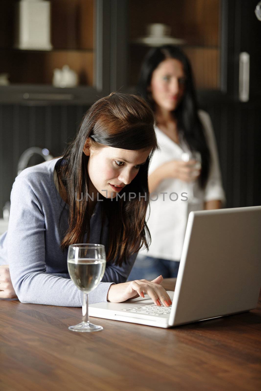 Two attractive friends looking at recipes on a laptop in their kitchen.