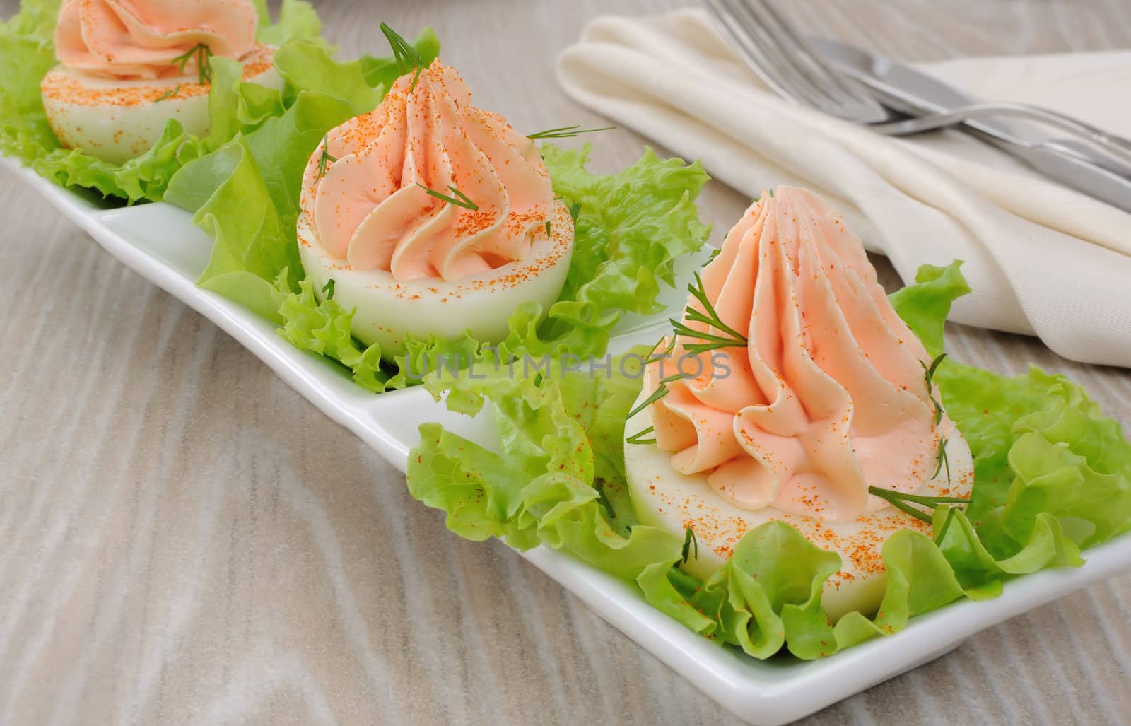 Eggs stuffed with pate salmon with red pepper in lettuce leaves