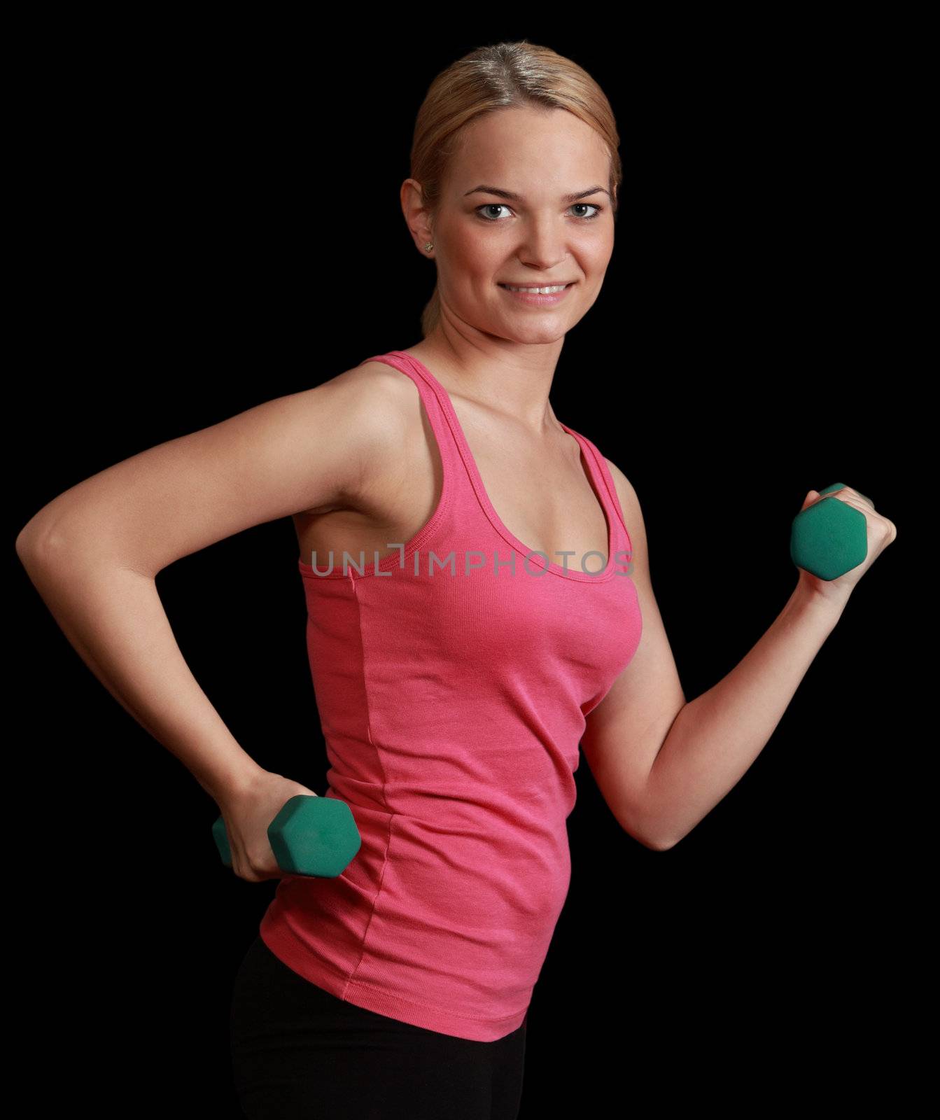 Young blonde woman doing exercise with dumbbells isolated against a black background.