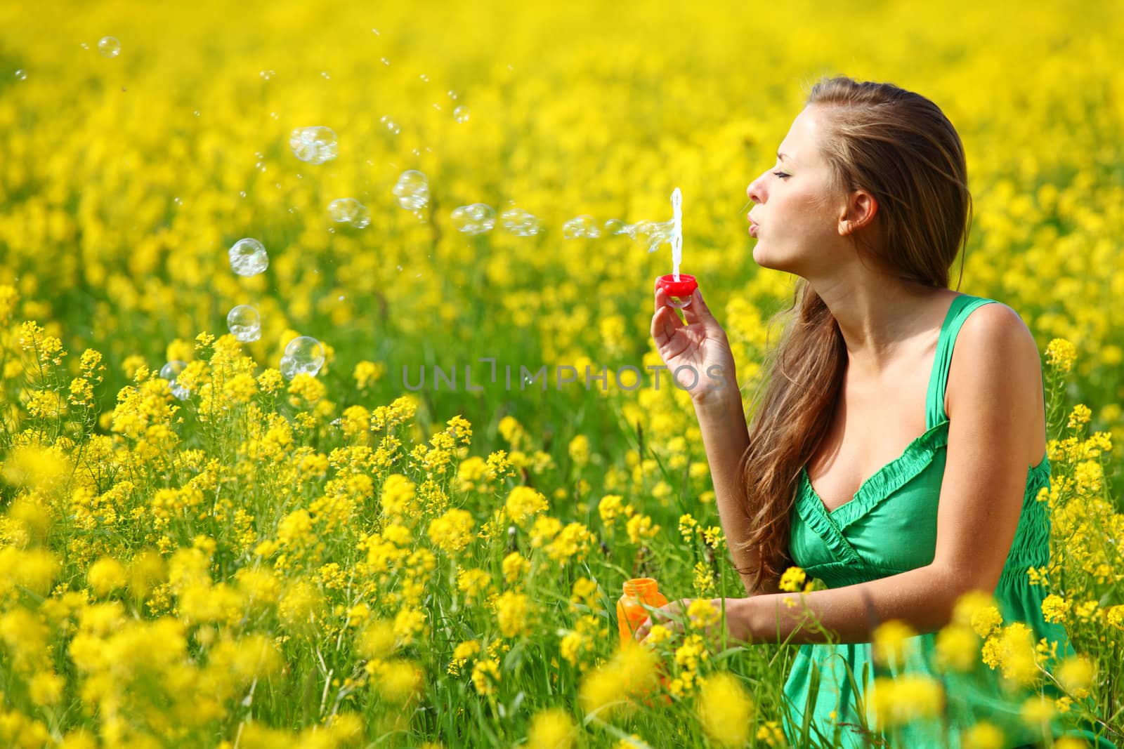 woman start soap bubbles on yellow flower field