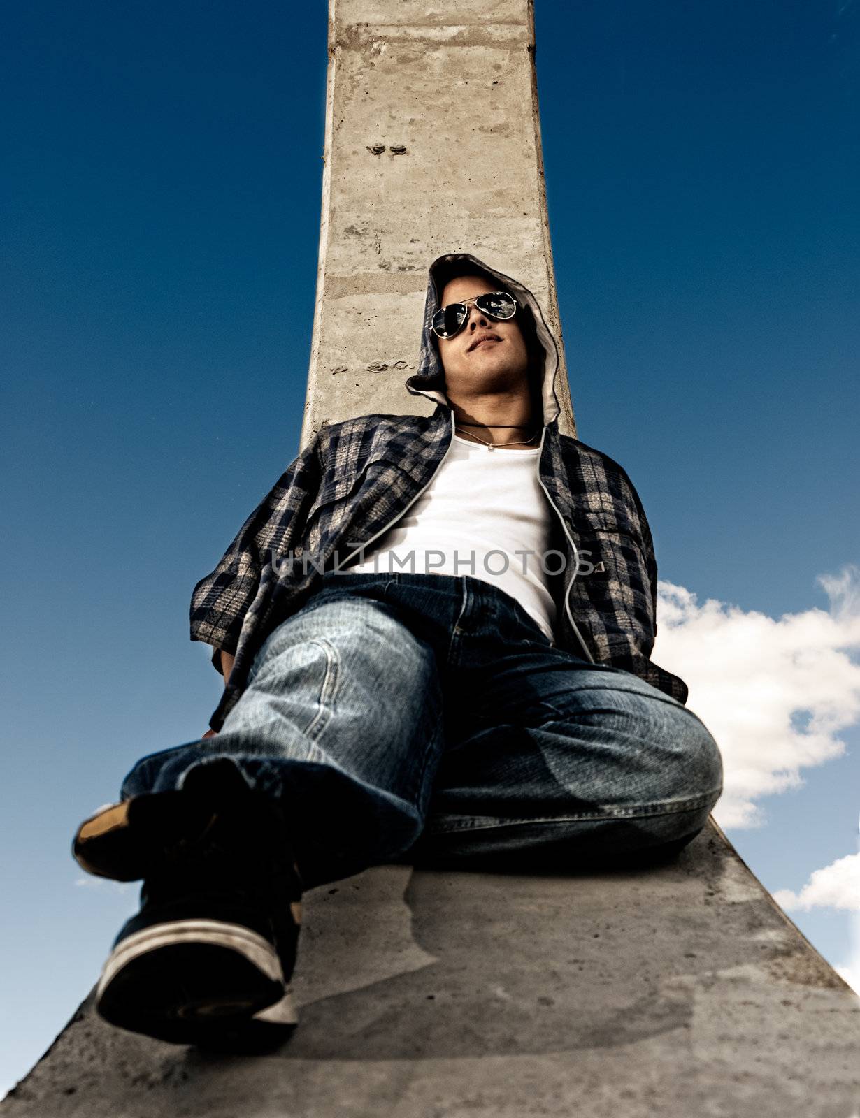 Young man urban fashion portrait over sky background by dgmata