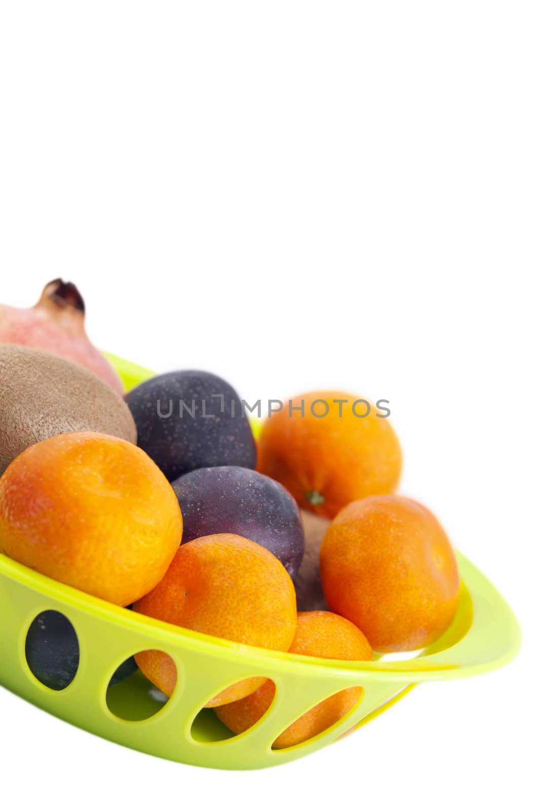 Mandarins, pomegranate, plums and kiwi fruits in the green plate isolated on white background