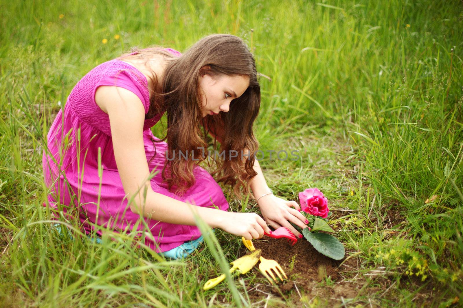 girl grow flower on green field