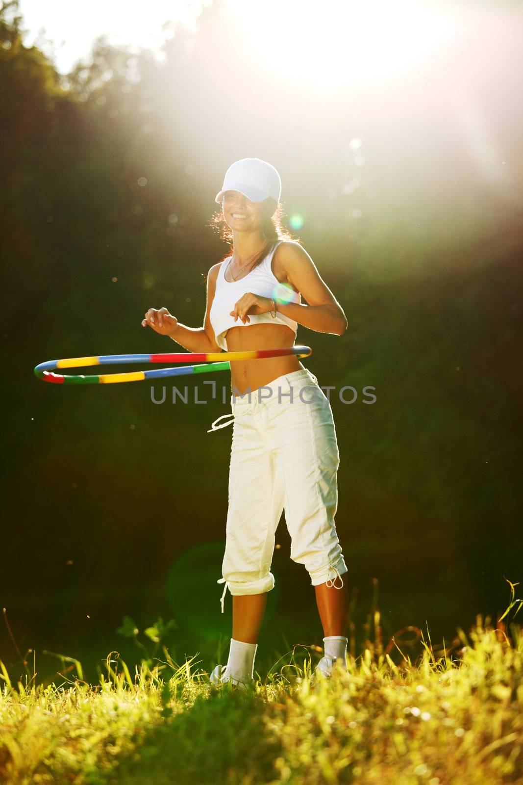 woman rotates hula hoop on nature background