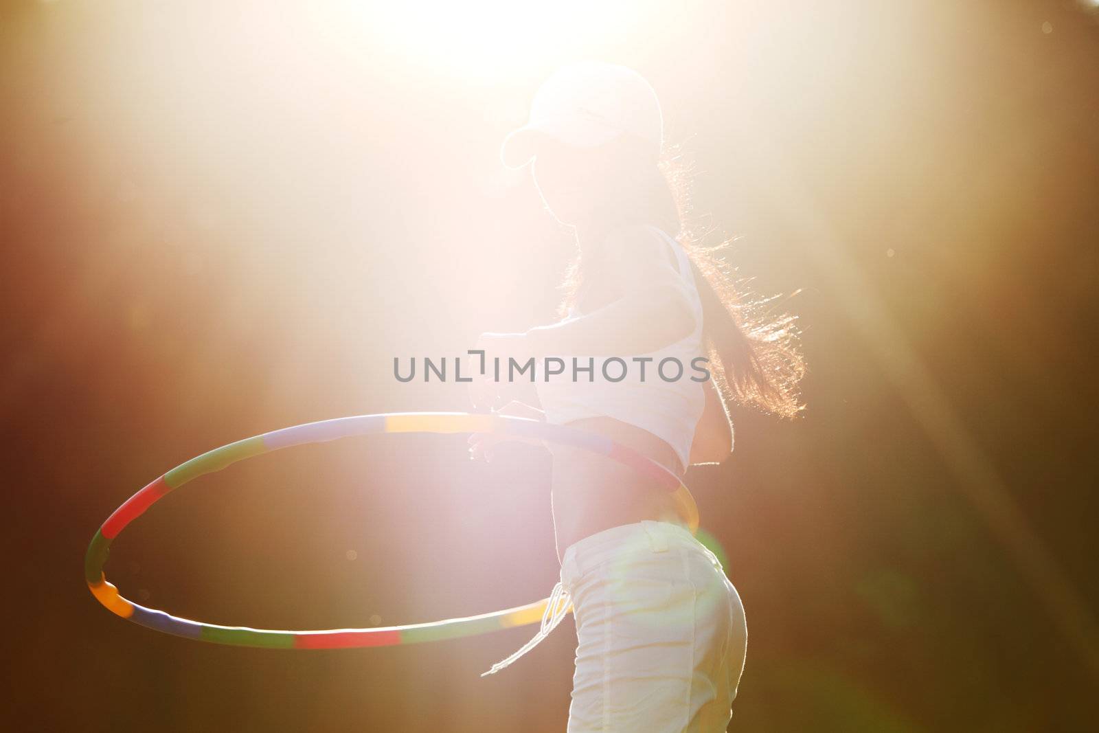 woman rotates hula hoop on nature background