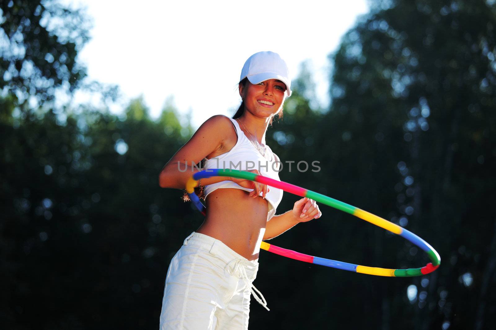 woman rotates hula hoop on nature background