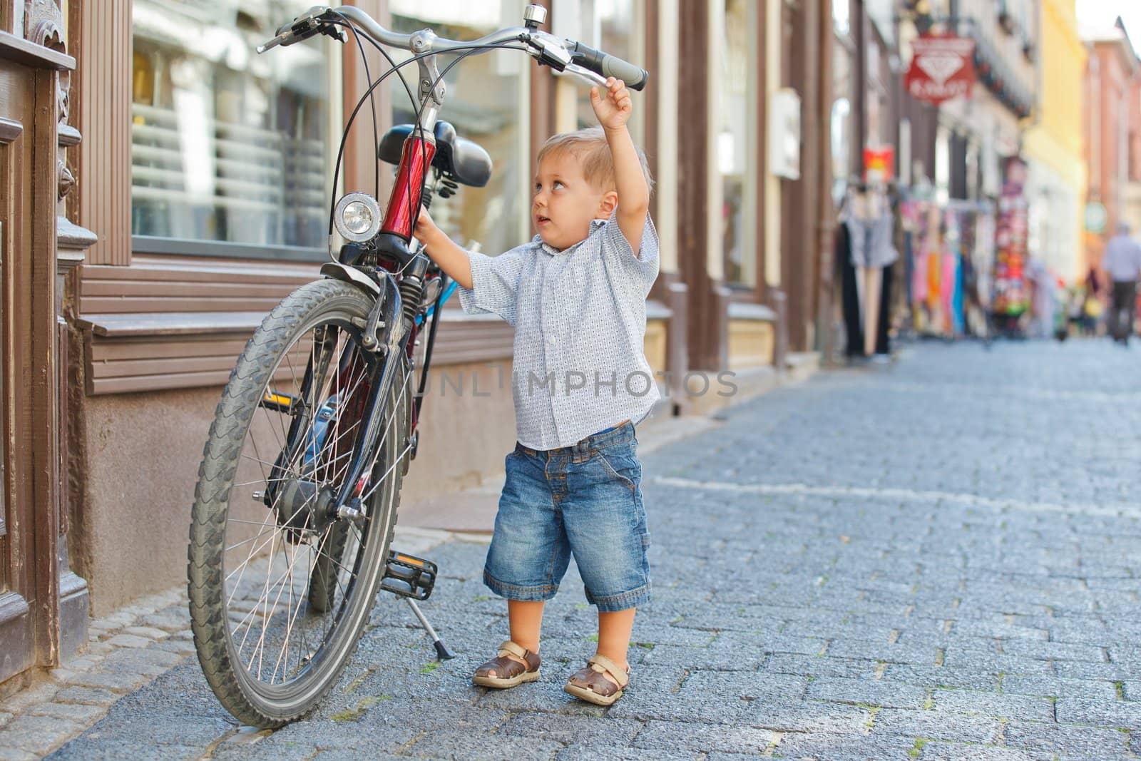 cute little boy with big bike outdoors in city street