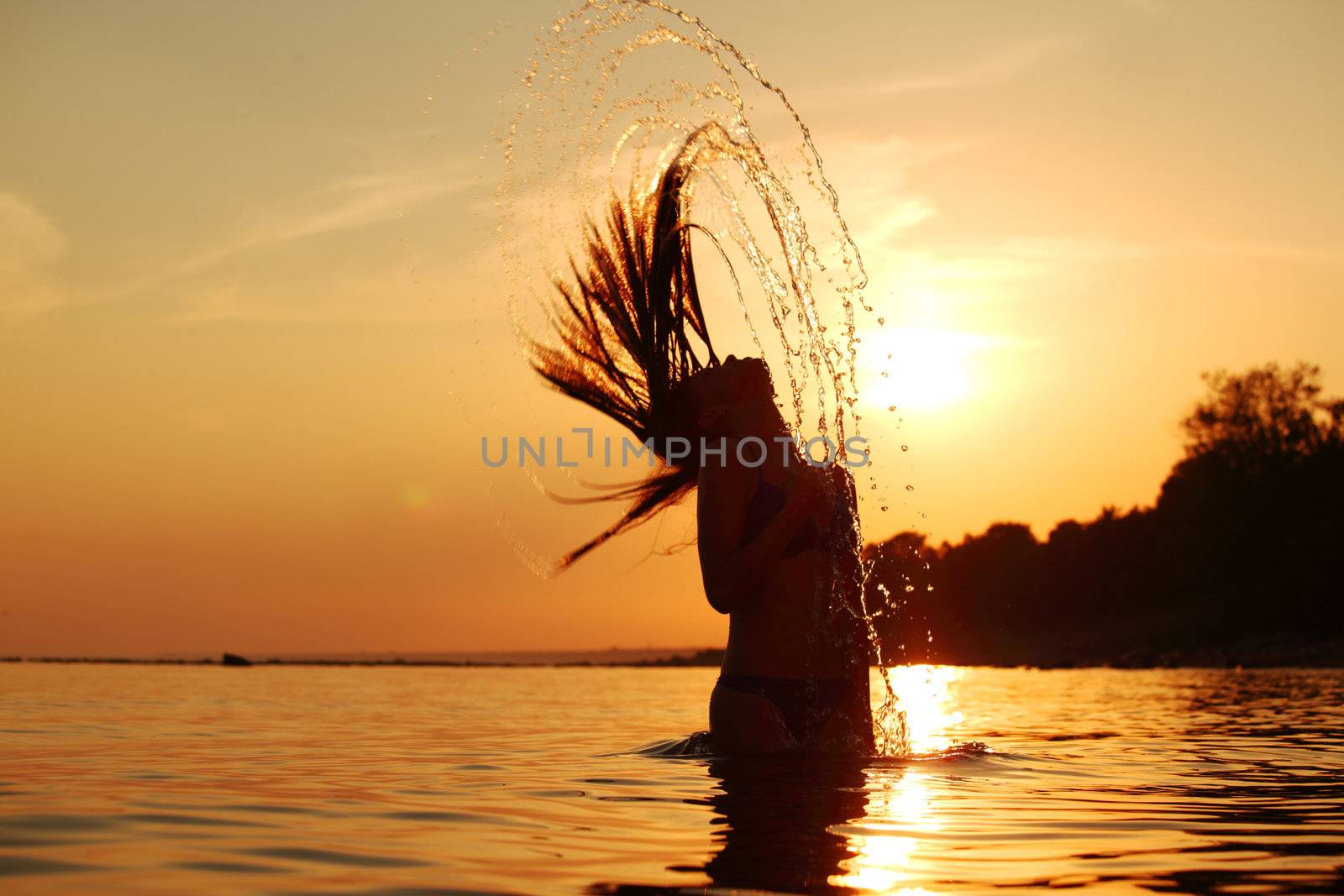 ocean woman in sunrise light splashing hair