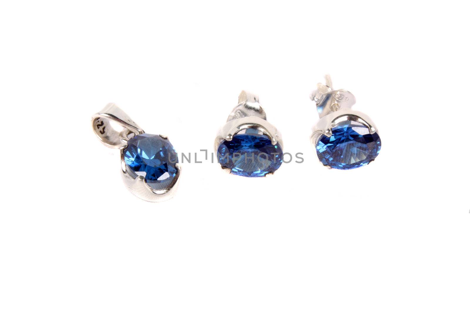 A set of silver jewelery with pendant and earrings made with precious blue gemstones, on white studio background.