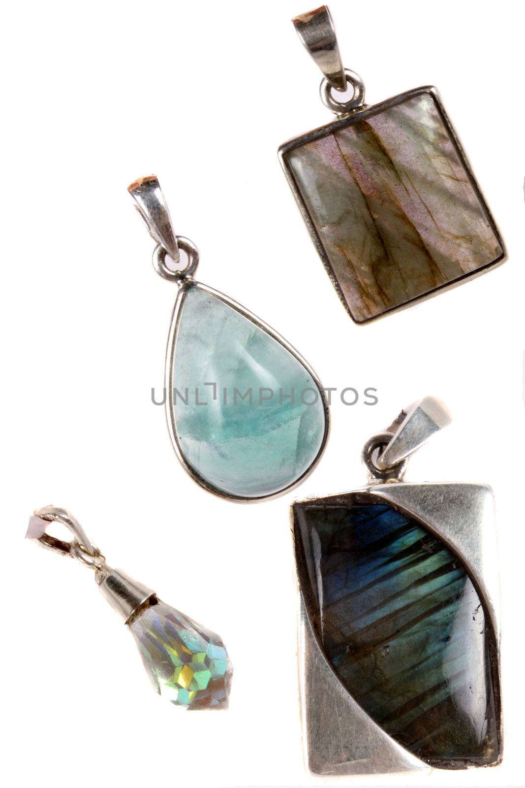 A set of silver pendants made with gemstones like aquamarine, labadorite and diamond, on white studio background.