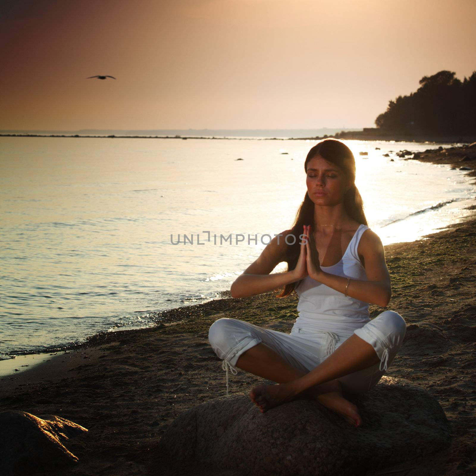 Young woman practicing yoga  near the ocean