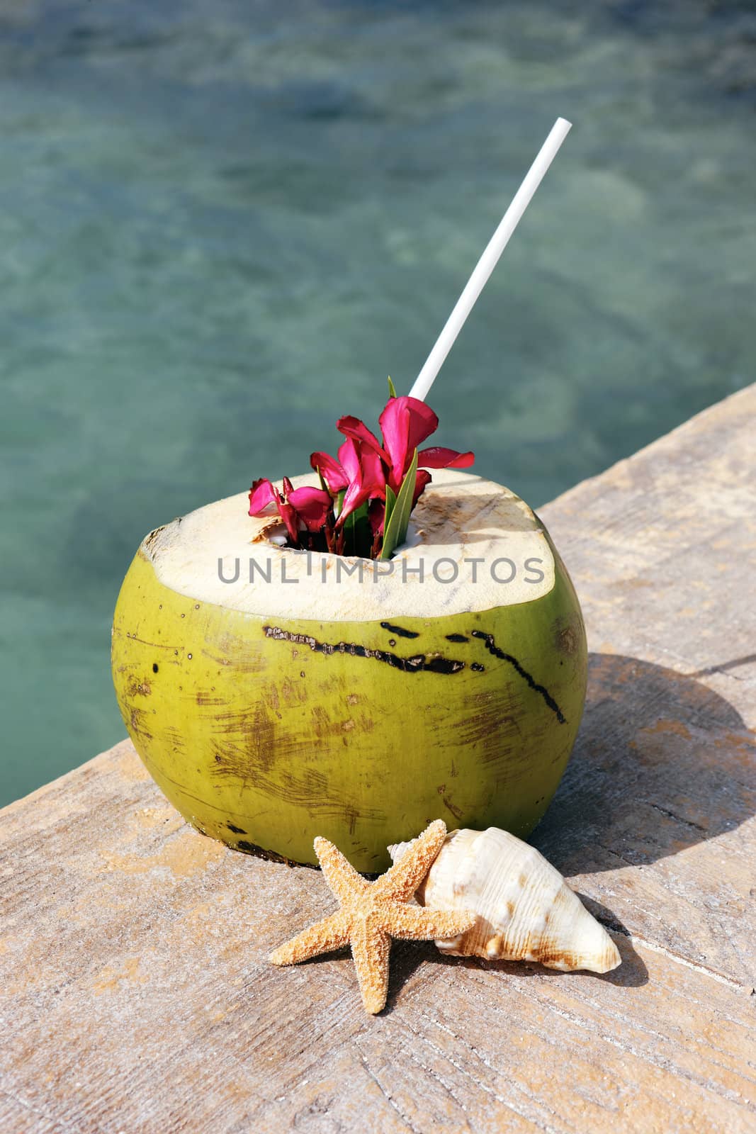 Coconut with drinking straw on a beach in summer 