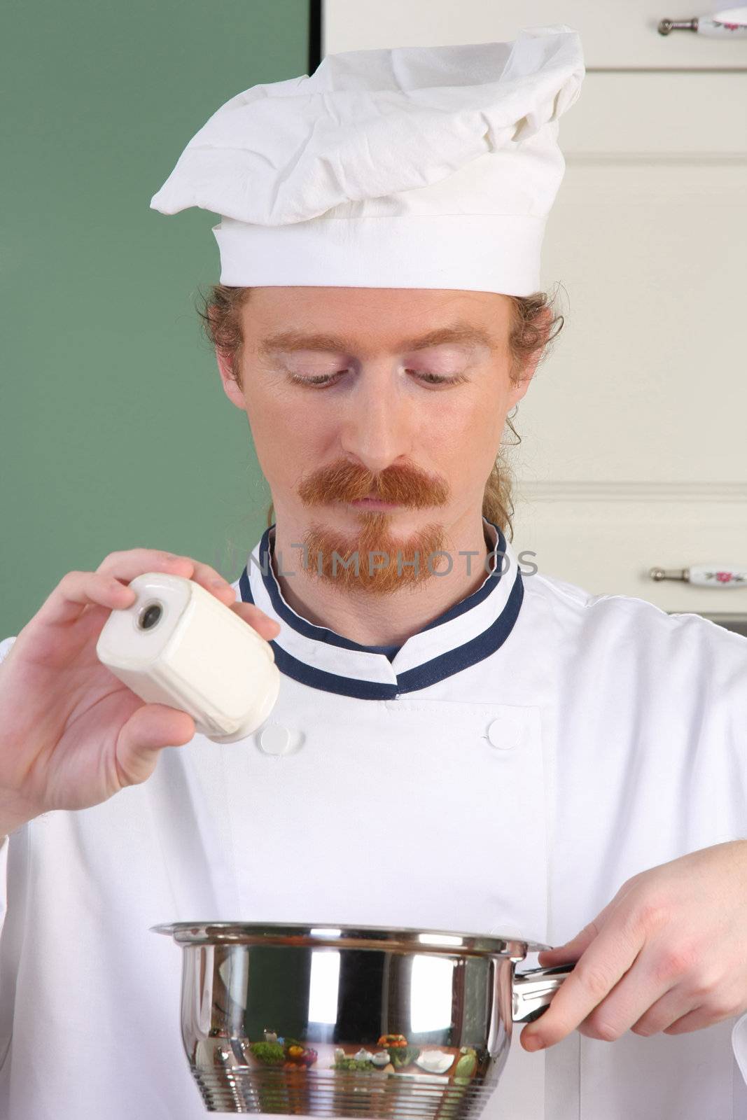 Young chef preparing lunch in kitchen by vladacanon